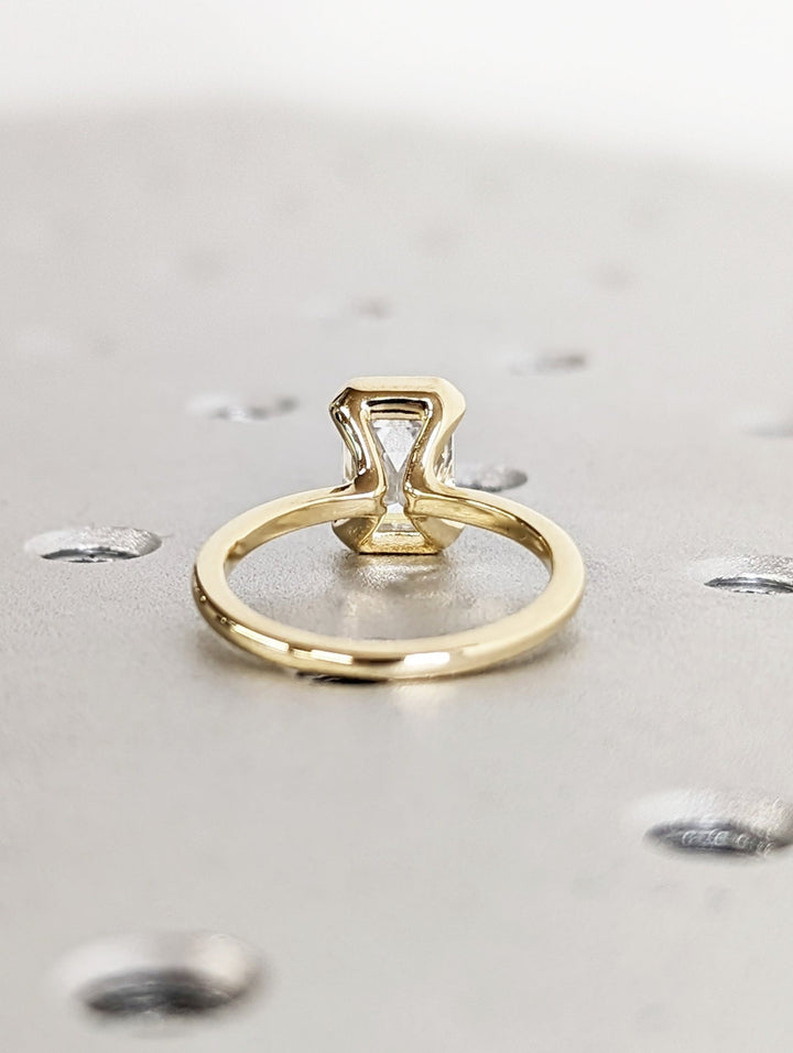 Elegant proposal ring with emerald cut half bezel design