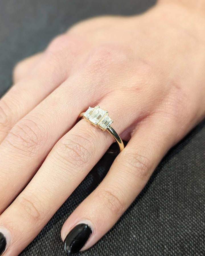 trilogy engagement ring with emerald center stone,