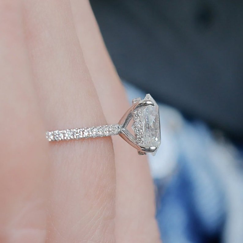 Oval hidden halo engagement ring shown on hand for true-to-life sizing