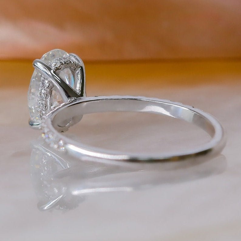 Oval hidden halo engagement ring viewed from the side