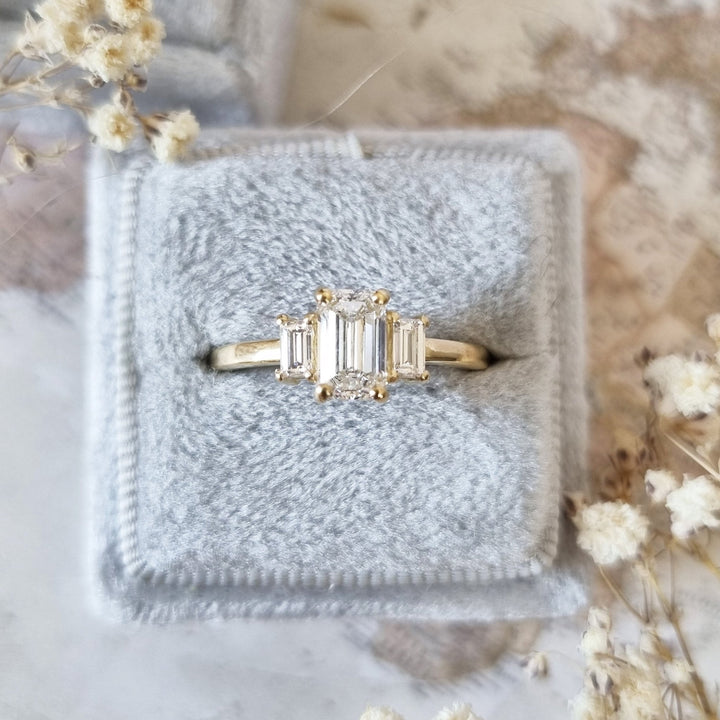 Emerald cut three stone engagement ring shown in real-life wear
